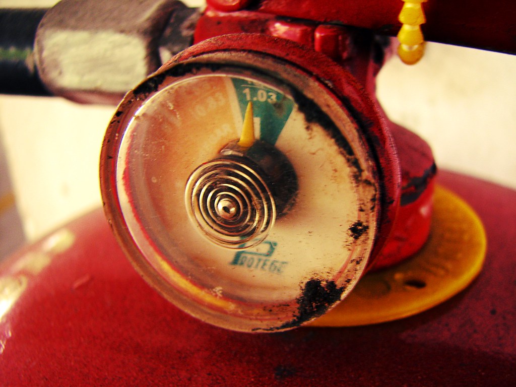 Red fire extinguisher mounted on a wall in a rented office room